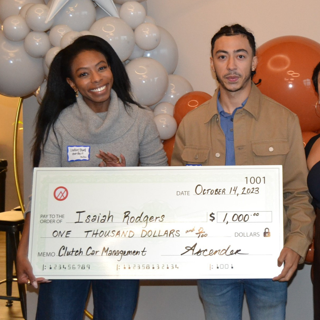 Isaiah Rodgers, founder of Clutch Car Management, holding a large check