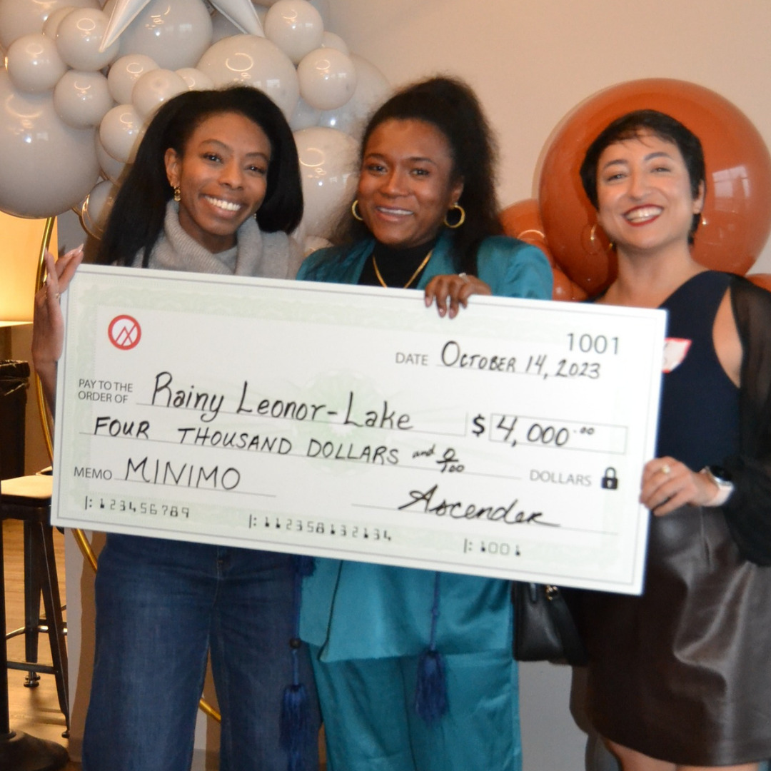 Rainy Leonor-Lake, owner of Minimo, holding a large check.